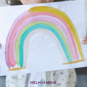 valokuvassa lapsi, joka pitää sateenkaaripiirrustusta kädessä. alla helminauhan logo.