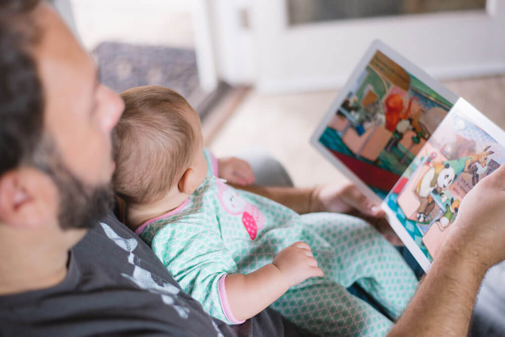Mies lukee lasten kirjaa vauvalle