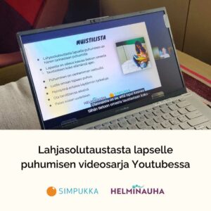 Pöydällä läppäri, jonka ruudulla pyörii Helminauhan videosarjan luento. Otsikkoteksti: Lahjasolutaustasta lapselle puhumisen videosarja Youtubessa. Alla Simpukan ja Helminauhan logot.